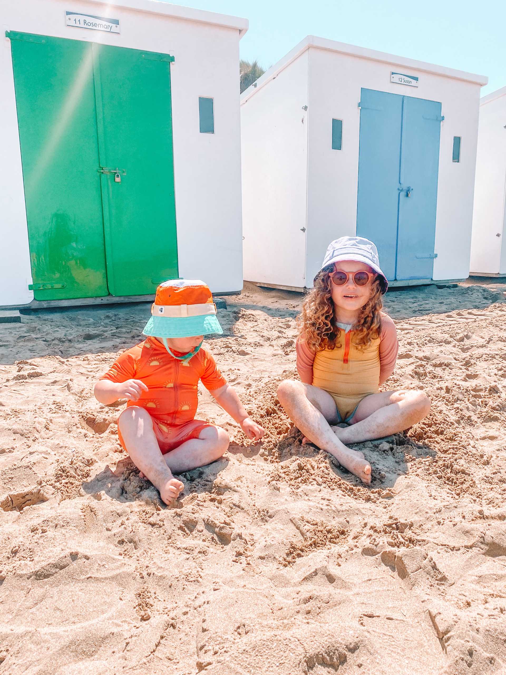 Two kids having fun on the beach as a summer activity wearing Grass & Air.